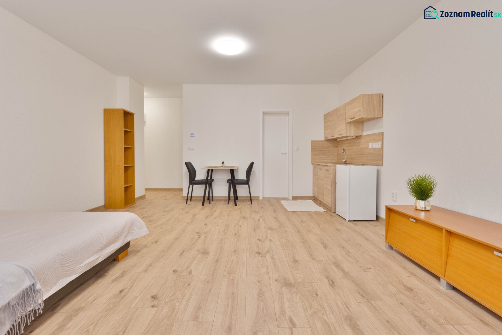 Studio apartment with a kitchenette, furniture, and flooring with a wood design.
