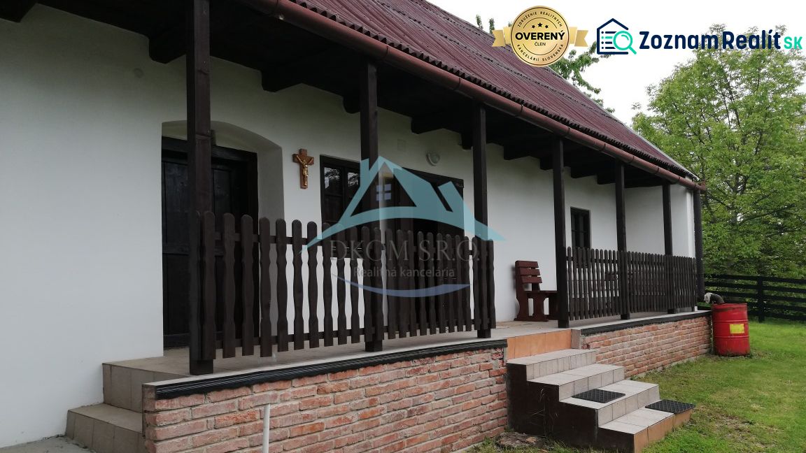 Family house with a terrace, wooden fence, and brick foundation in a natural setting.
