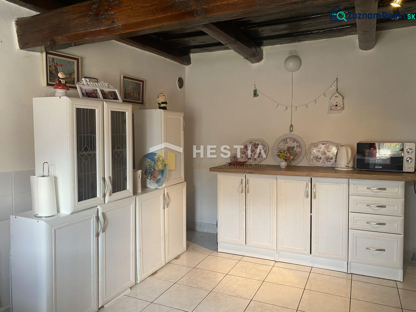 A kitchen in a family house with wooden beams and white cabinets.