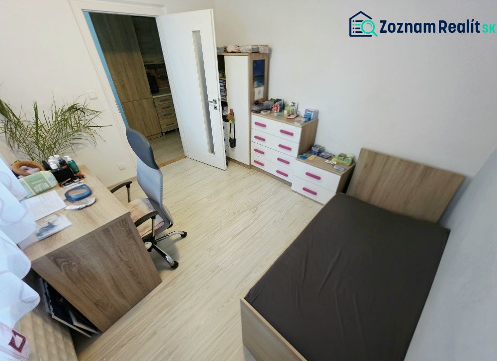 A room in a 4-room apartment with wooden floor decor, a bed, and a desk.