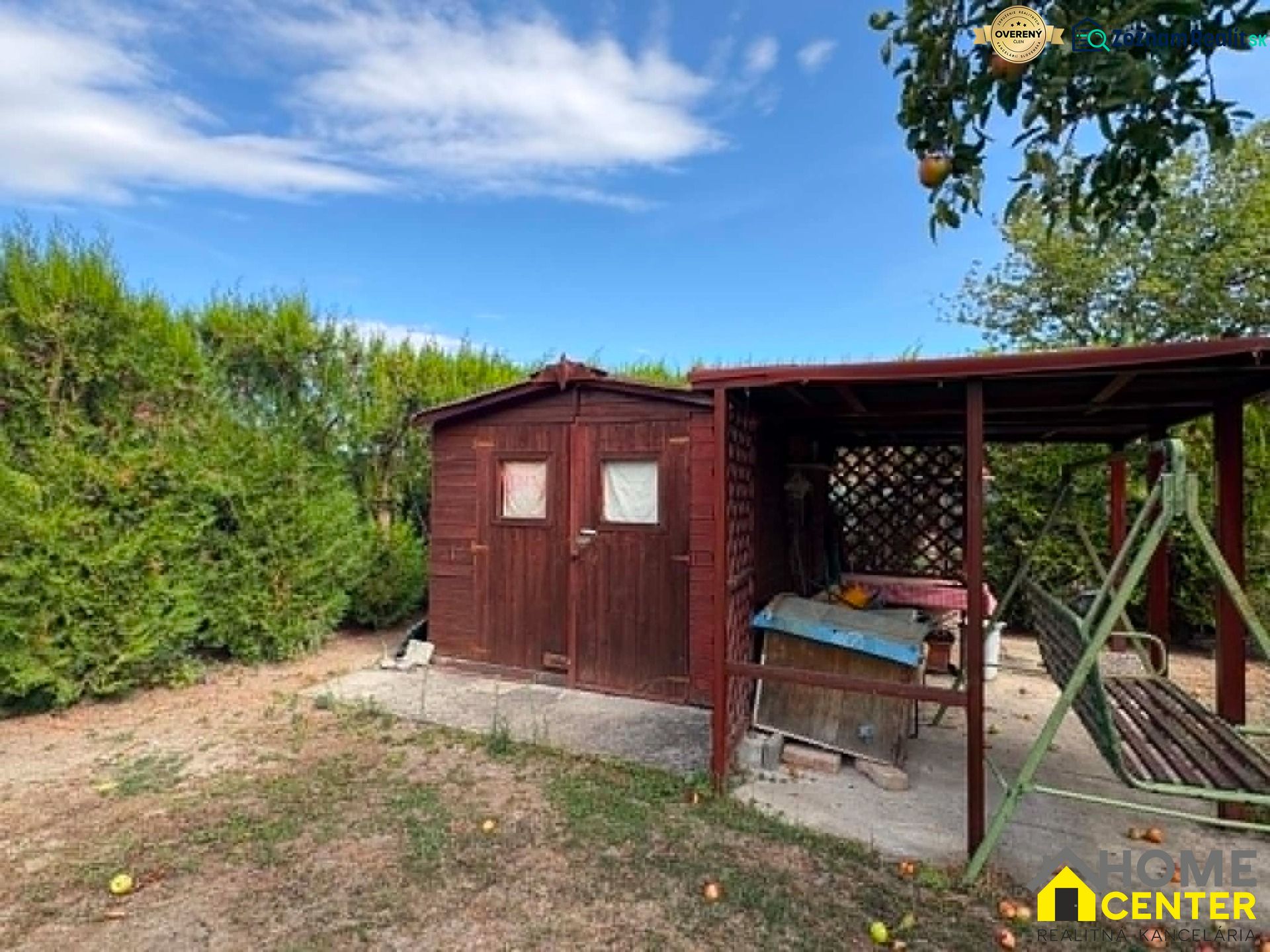 A wooden gazebo and a swing in the garden in Komárno with fruit trees.