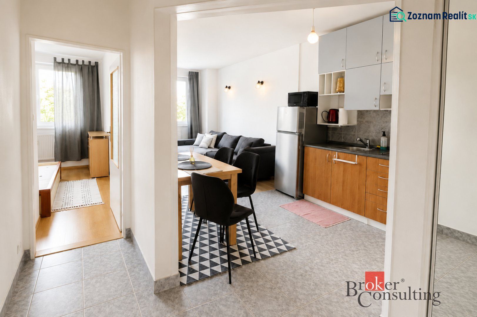 Interior of a 2-room apartment with a kitchen, living room, and wooden decor flooring.