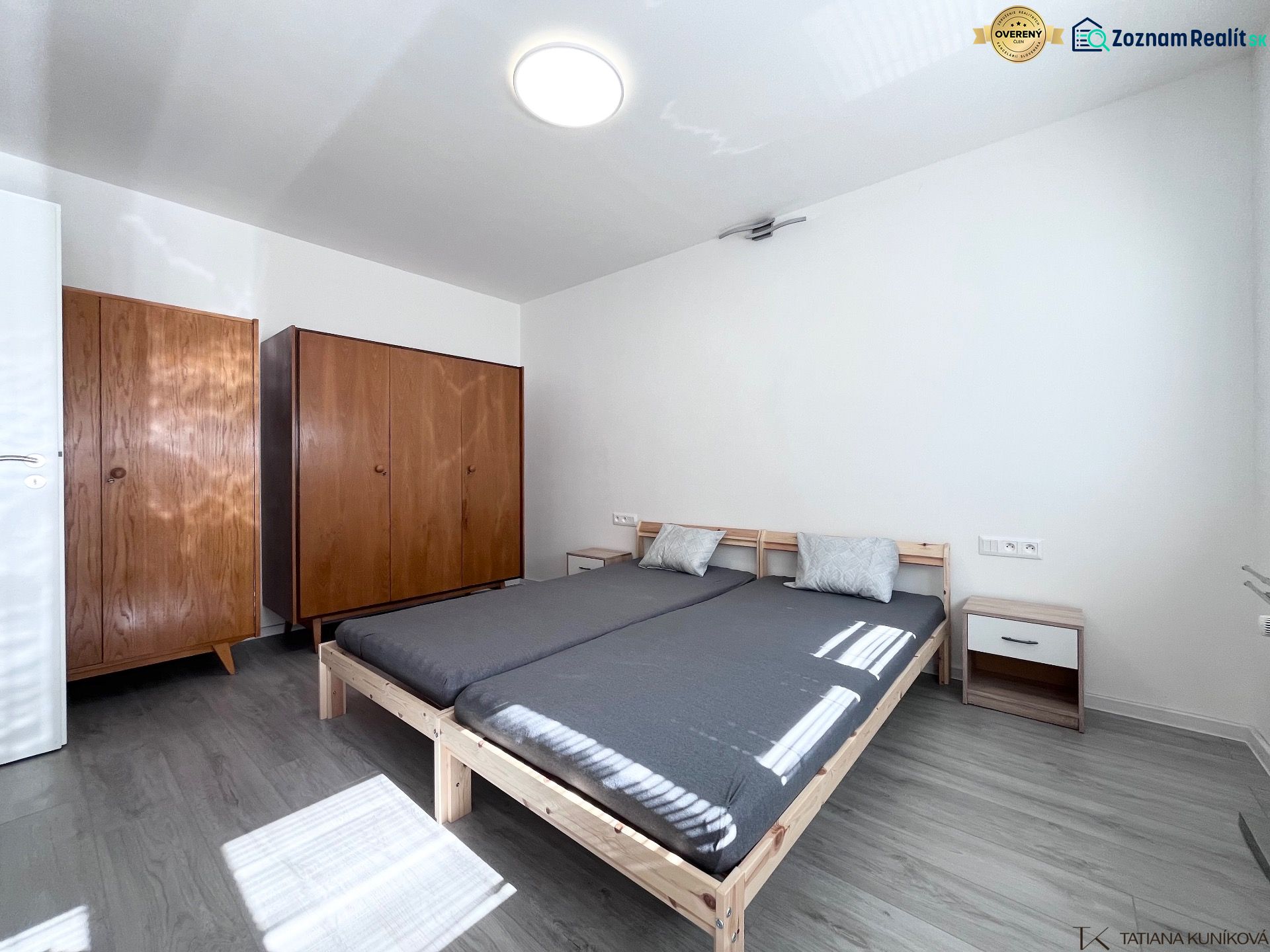 A bedroom with a bed, wooden wardrobes, and a floor with a wooden decor in a 3-room apartment.