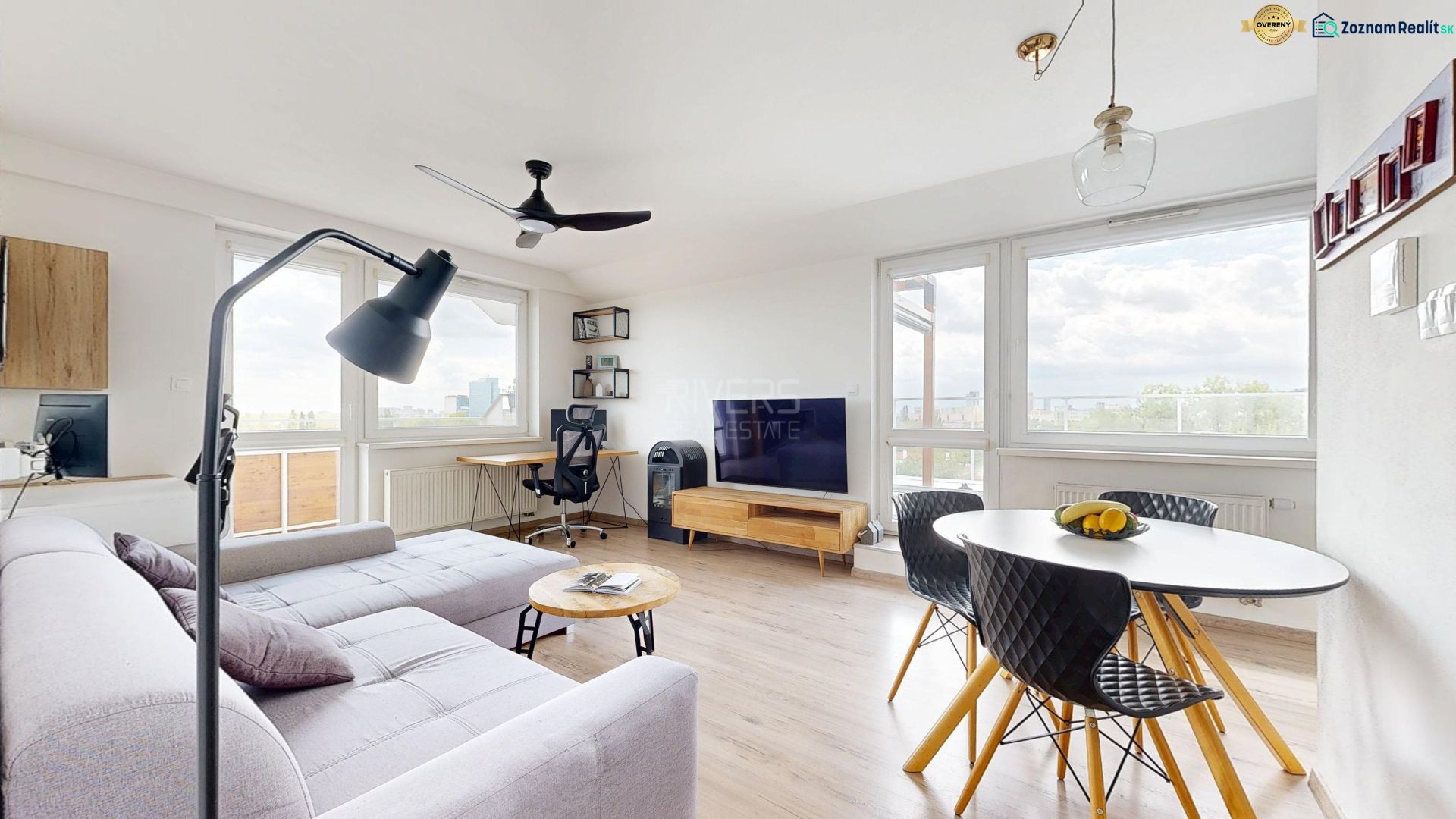 Living room in a three-room apartment with a wooden decor floor and a light-colored sofa set.
