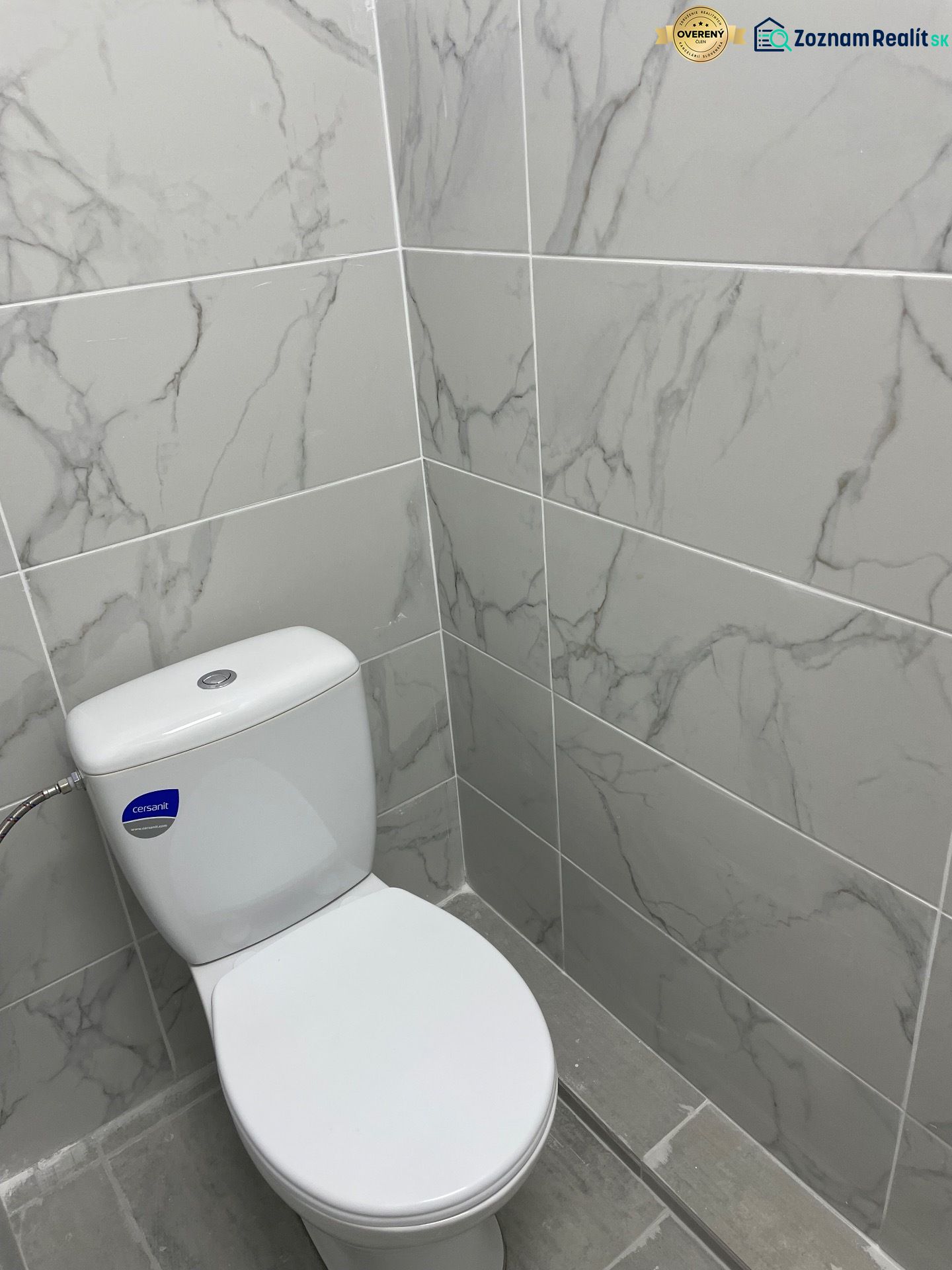 A restroom with marble tiles in commercial spaces, gray floor.