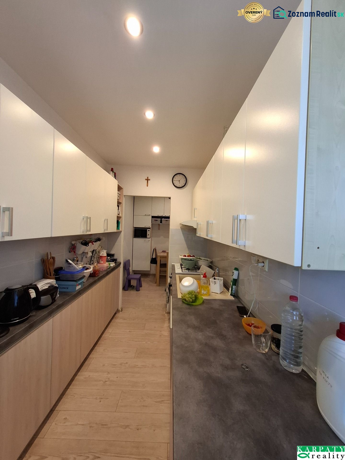 A kitchen in a 3-room apartment with white cabinets and a wood-patterned floor.