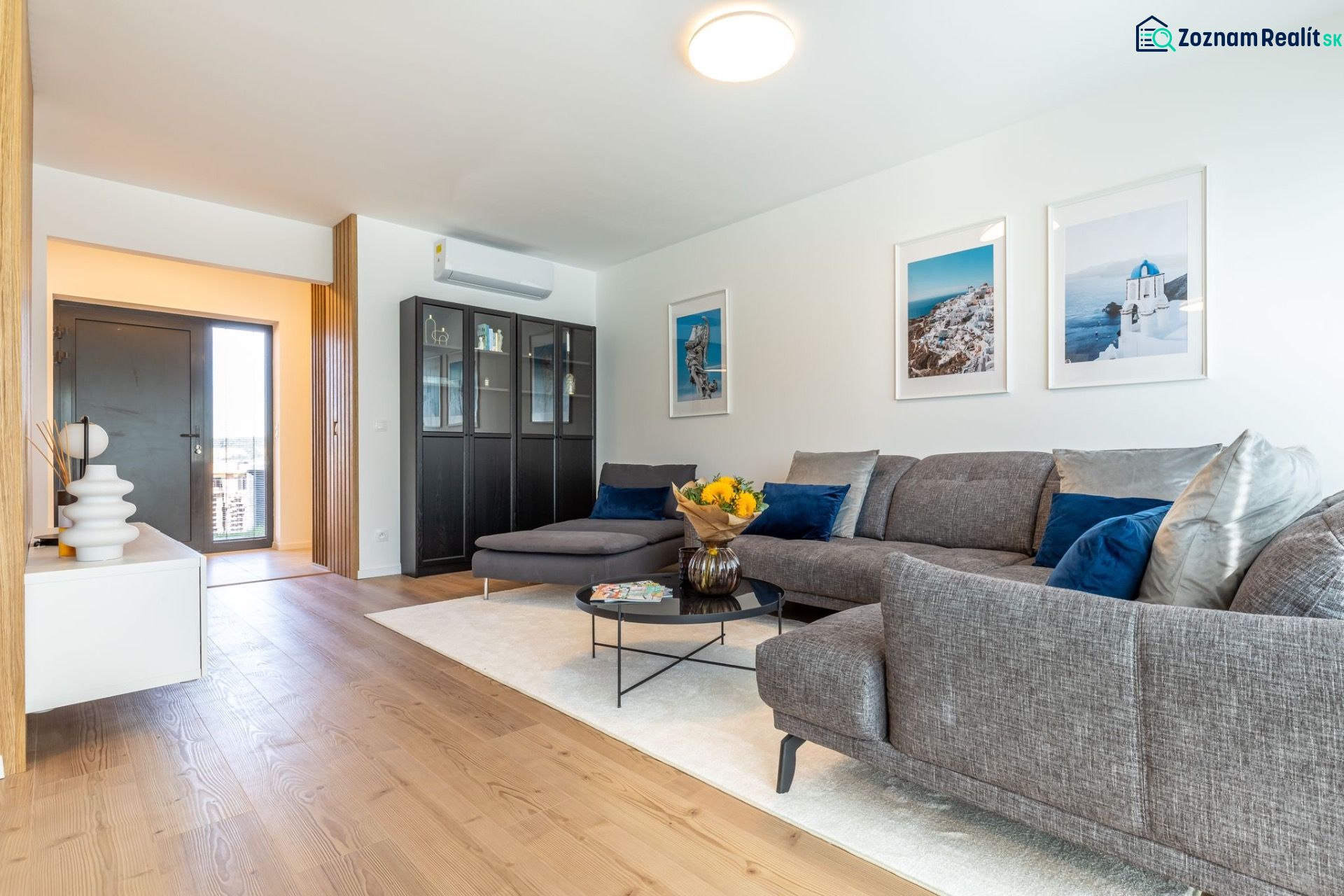 Living room in a family house with a wooden decor floor, a sofa, and decorative items.