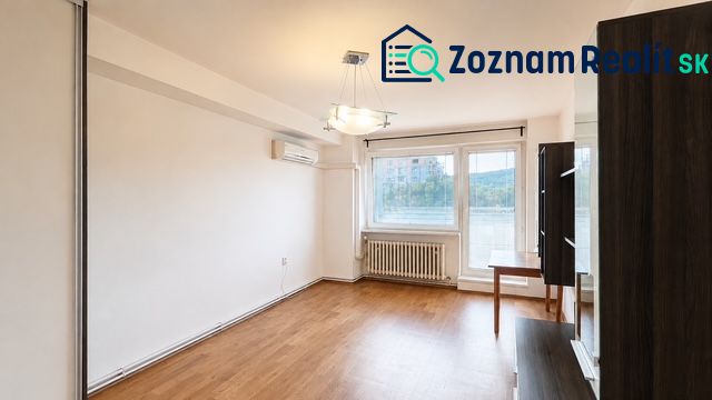 Living room with wood-patterned flooring, air conditioning, and a large window in a 3-room apartment.