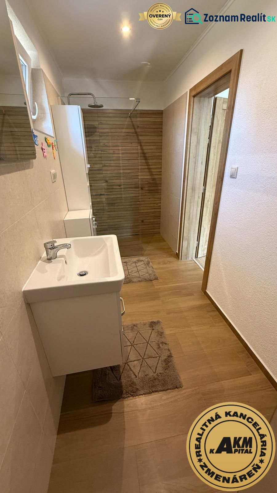 A bathroom in a family house with a sink, a shower corner, and a floor with a wooden decor.