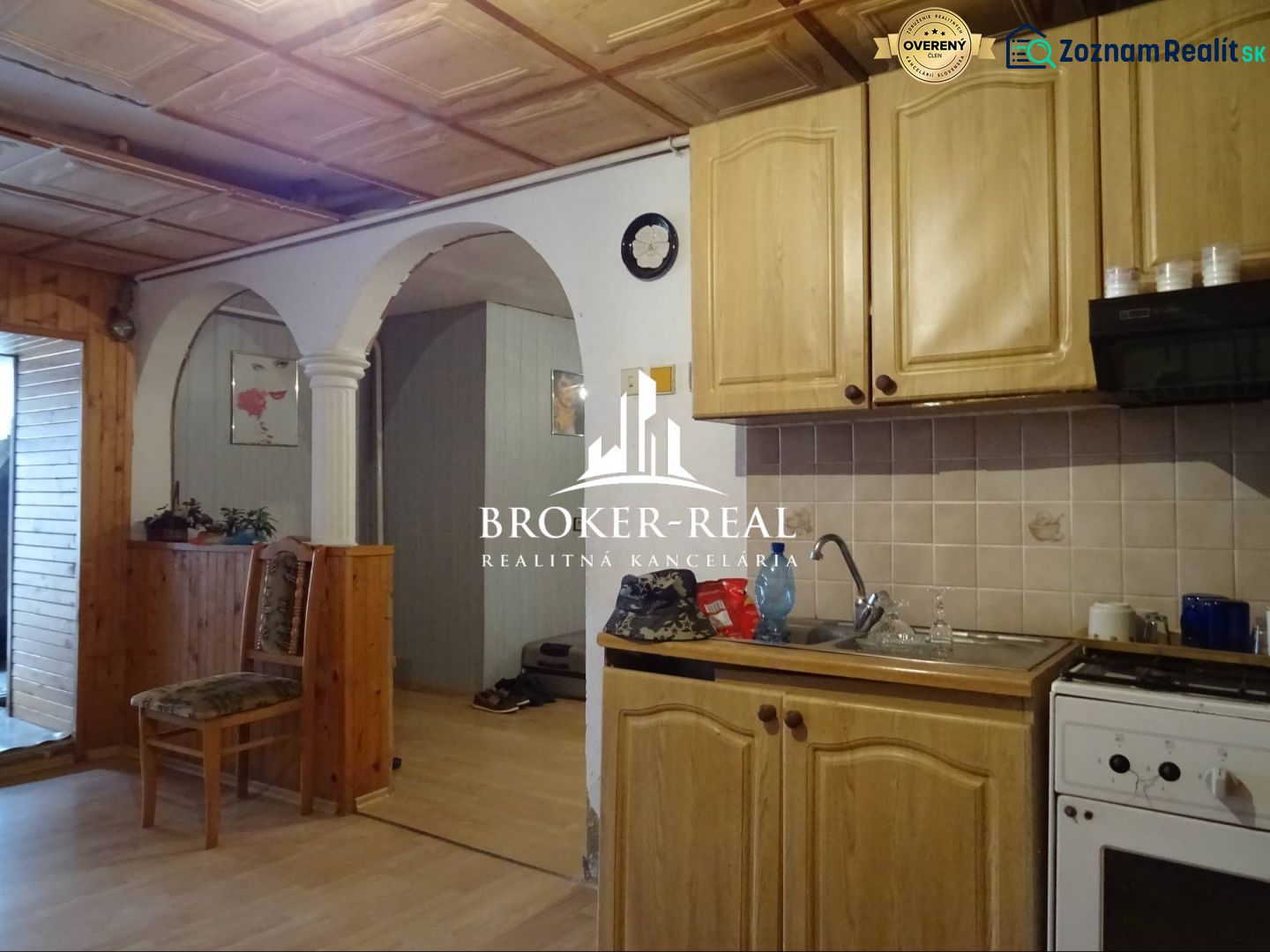 A kitchen with an arched doorway, wooden cabinets, a floor with a wooden design, family house.