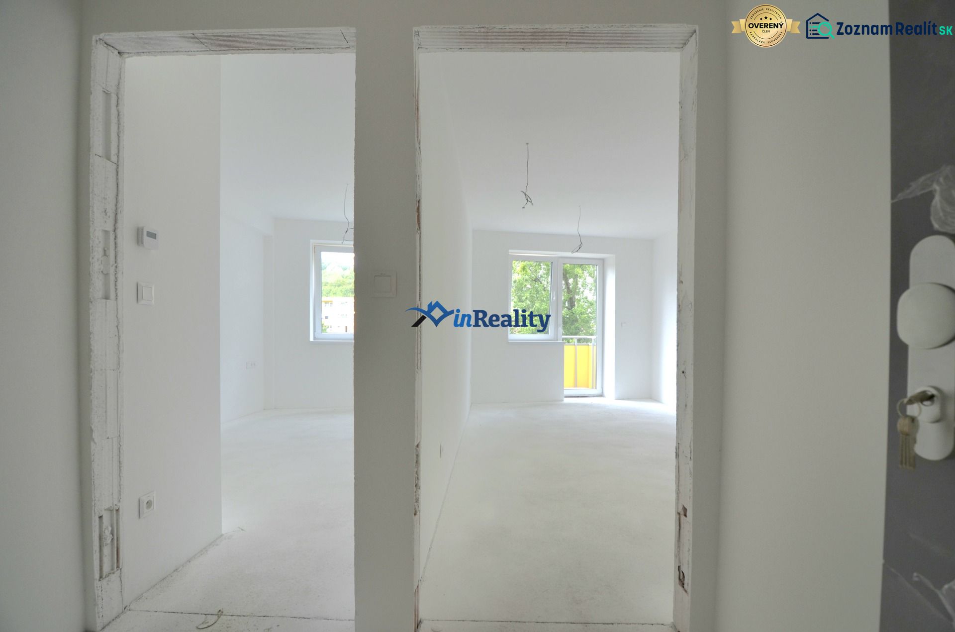 A white interior of an empty 2-room apartment with a window and balcony doors.