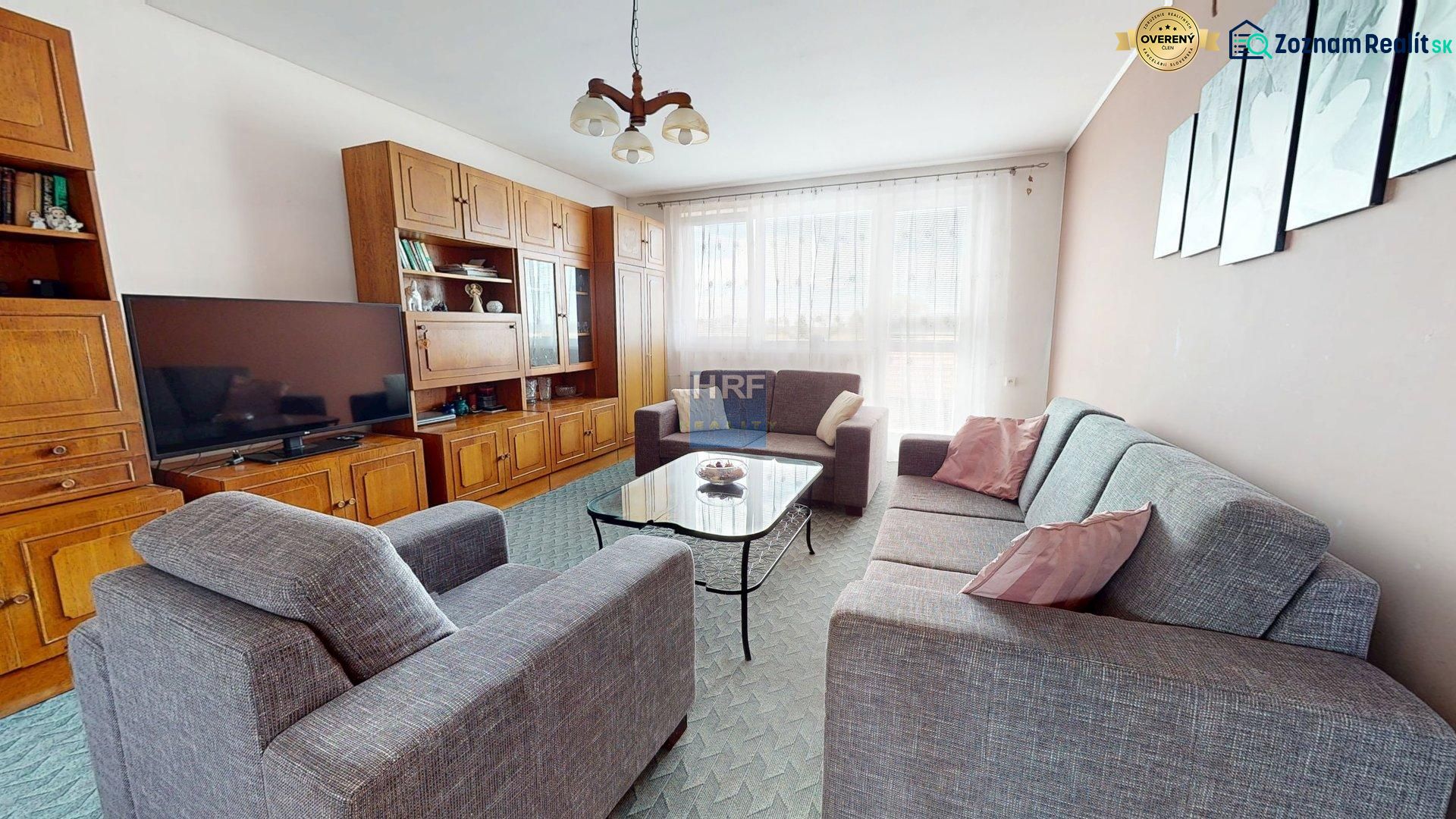 Living room with a gray sofa, wooden wall, and television in a family house.