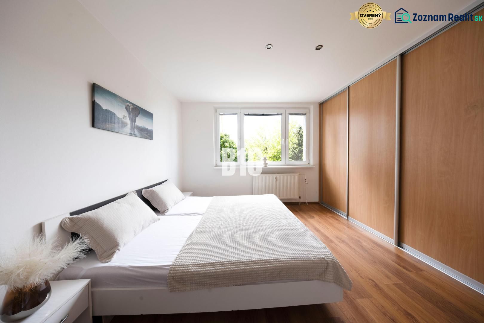 A bright bedroom in a 3-room apartment with a large wardrobe and a wooden decor floor.