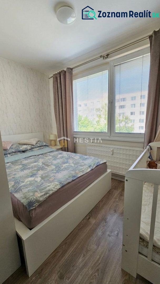 Bedroom in a two-room apartment with large windows and a wooden decor floor.