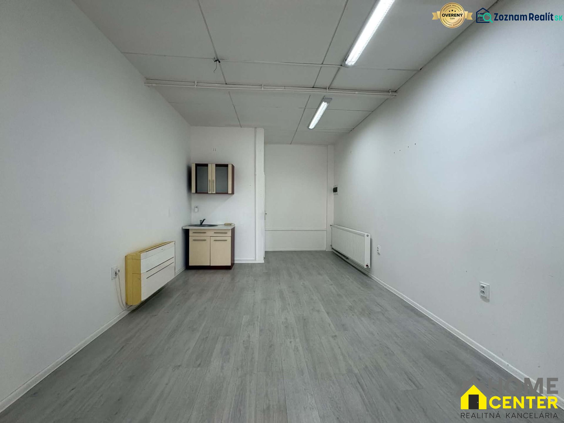 Commercial premises with a wooden decor floor also include a sink and cabinets.