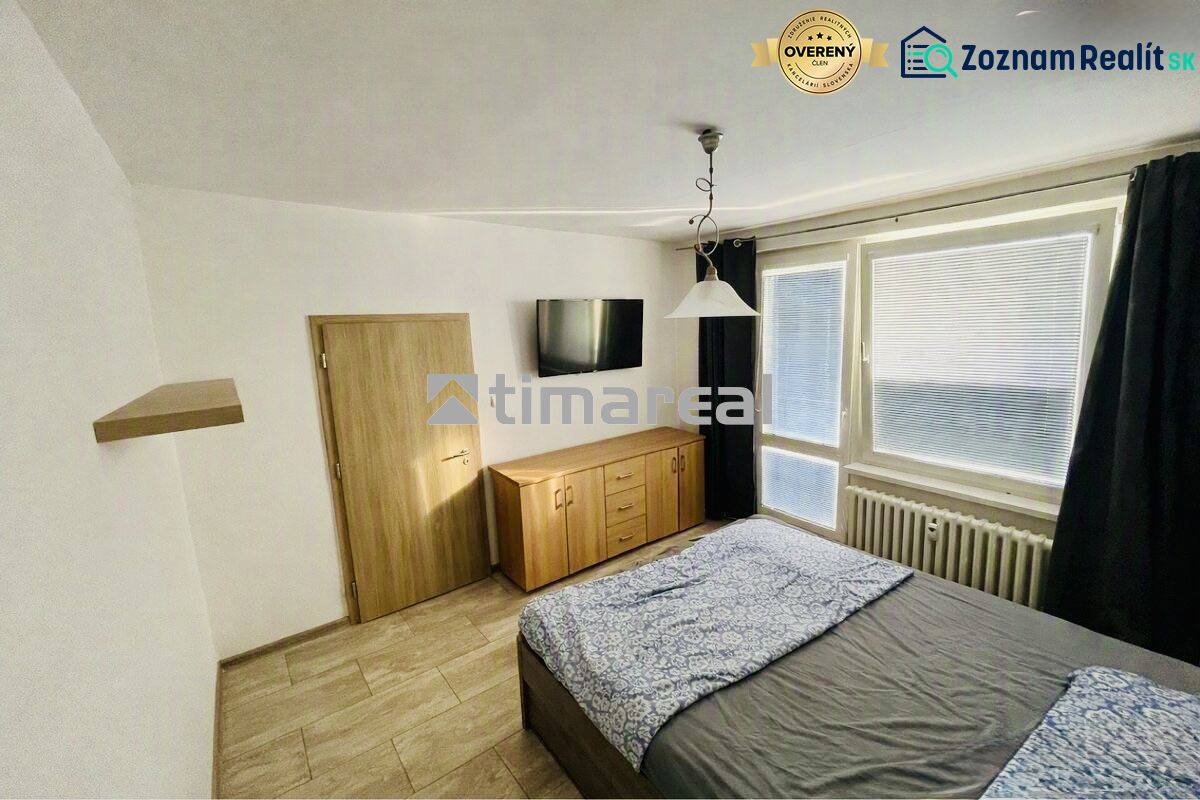 A bedroom with a wood-patterned floor, a bed, a dresser, and a television in a 3-room apartment.