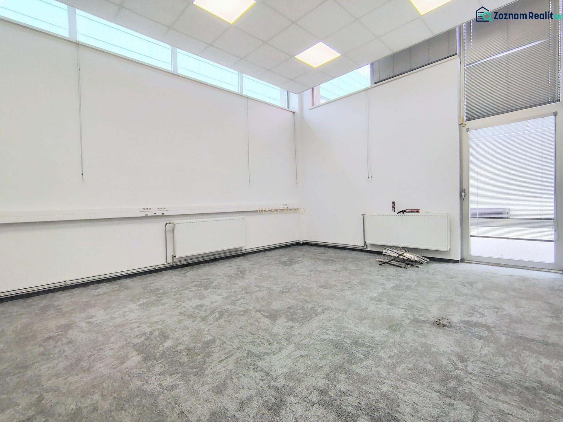 Interior of a commercial space with large windows and a gray floor with decor.
