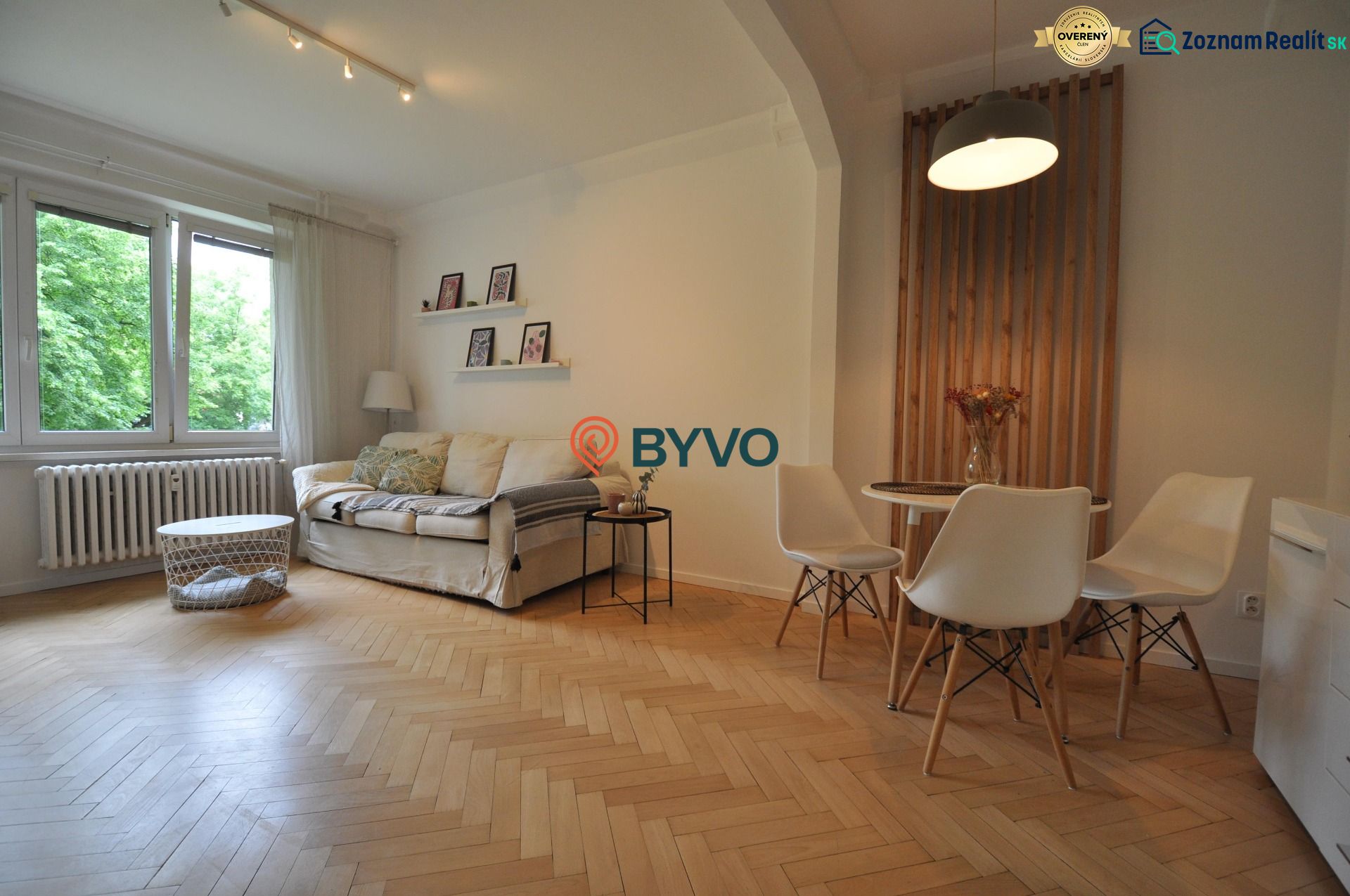 Living room with wood-patterned flooring, a sofa, and a dining table in a two-room apartment.