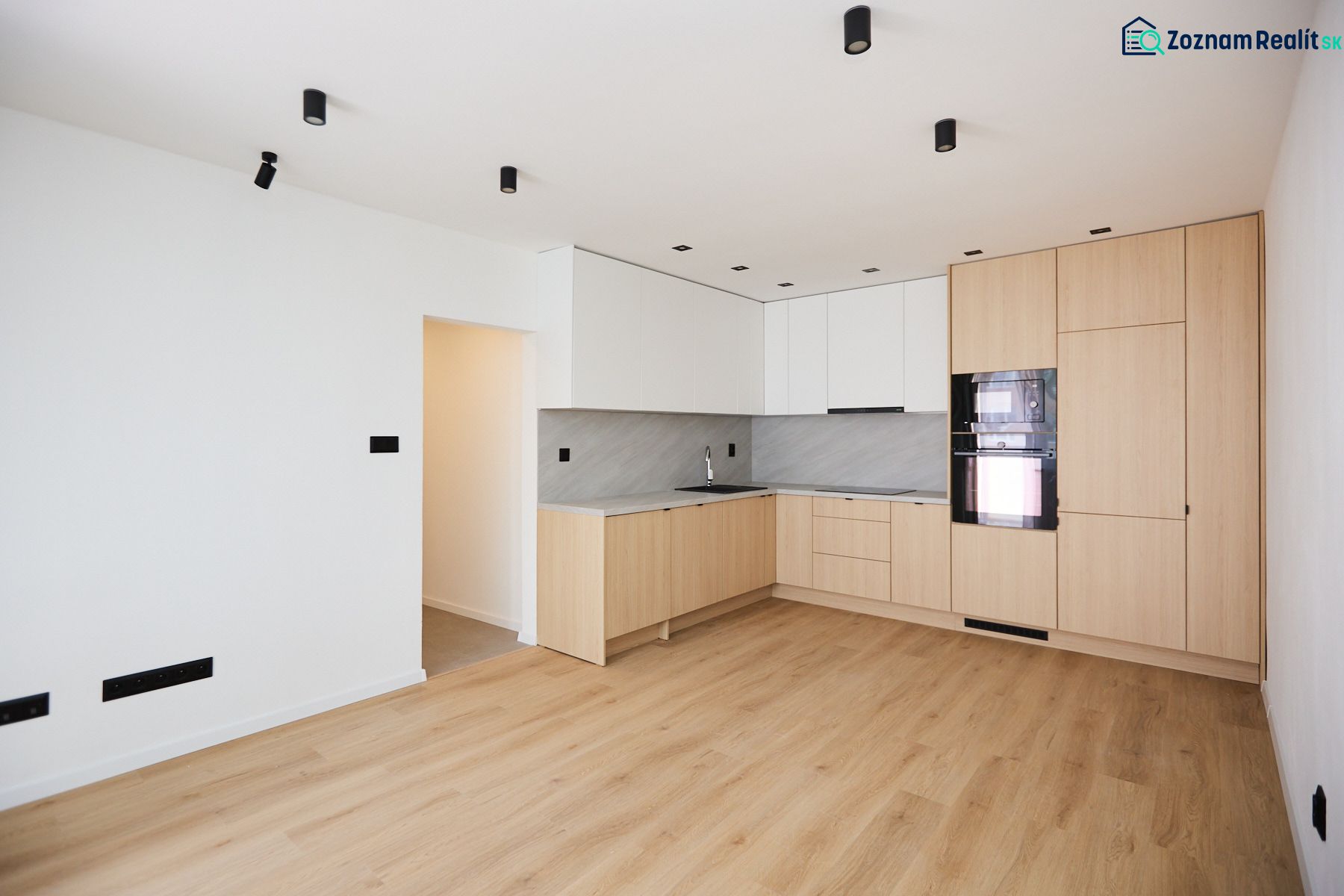 A kitchen in a 2-room apartment with a wooden decor floor and built-in appliances.