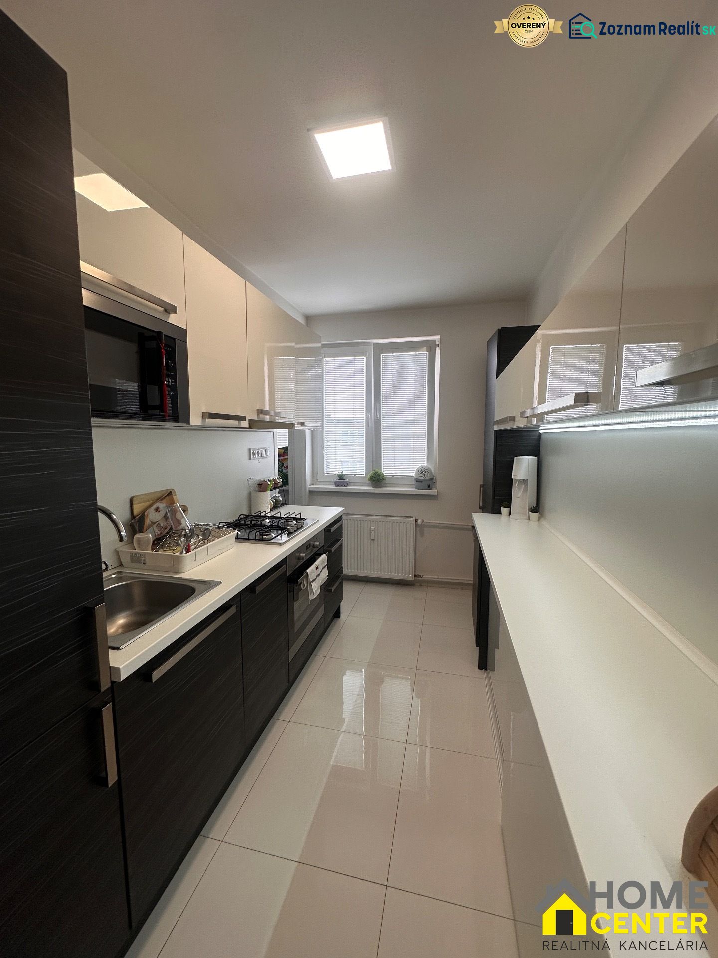 A kitchen in a 3-room apartment with built-in appliances and white tiles.