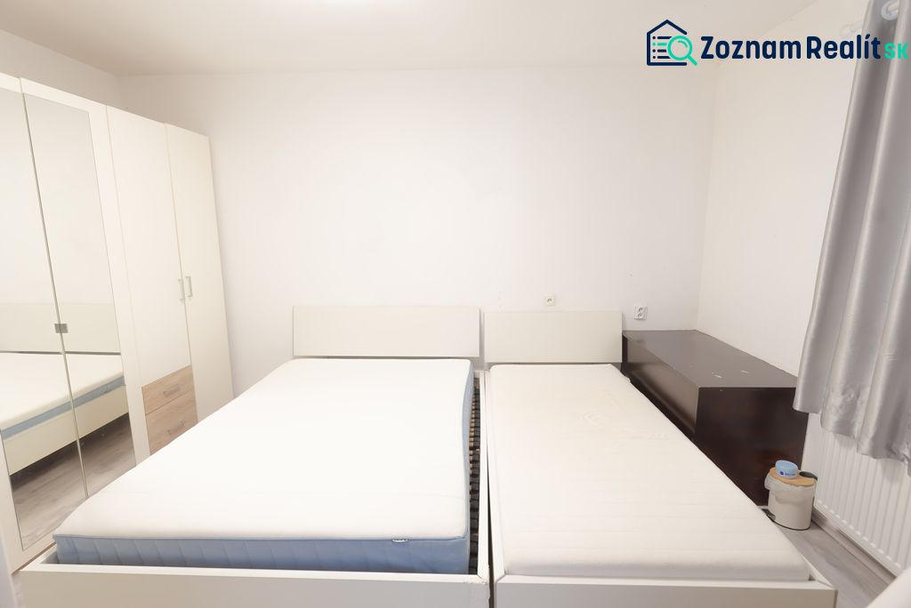 A bedroom in a family house with two beds, a large wardrobe, and simple furniture.