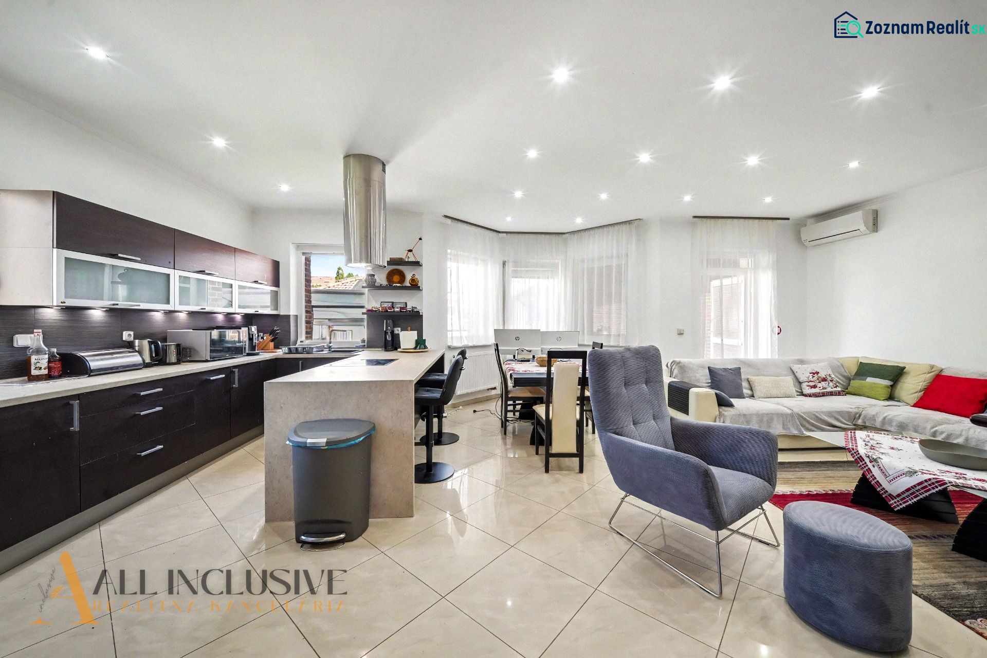 Living room in a family house with a kitchen, dining area, and a light-colored sofa.