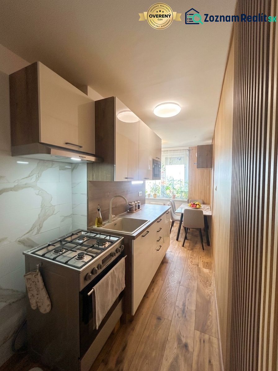 A kitchen in a 3-room apartment with a wooden decor floor and a dining area.