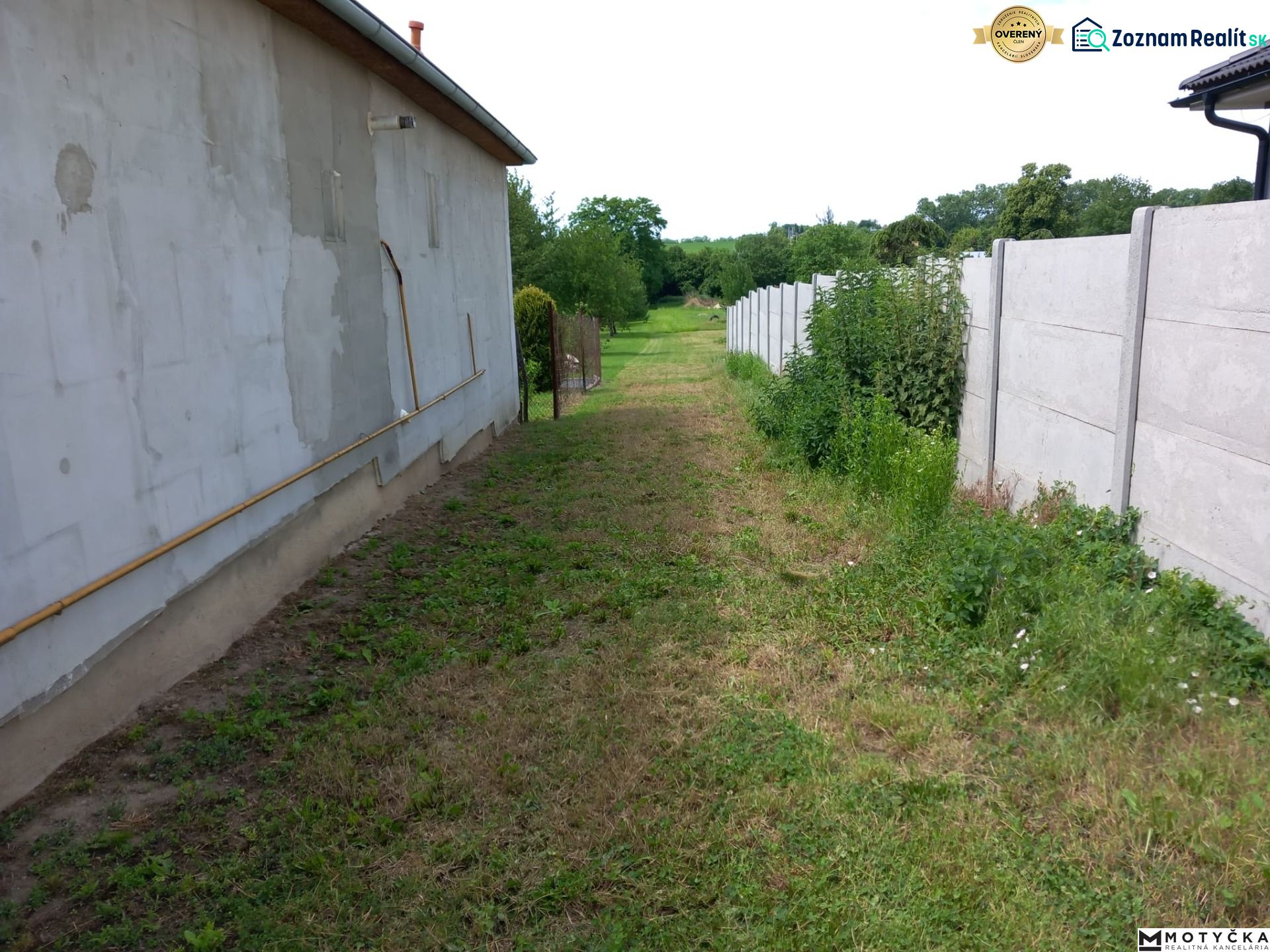 The back part of the building enclosed by a fence in Beladice, suitable for residential plots.