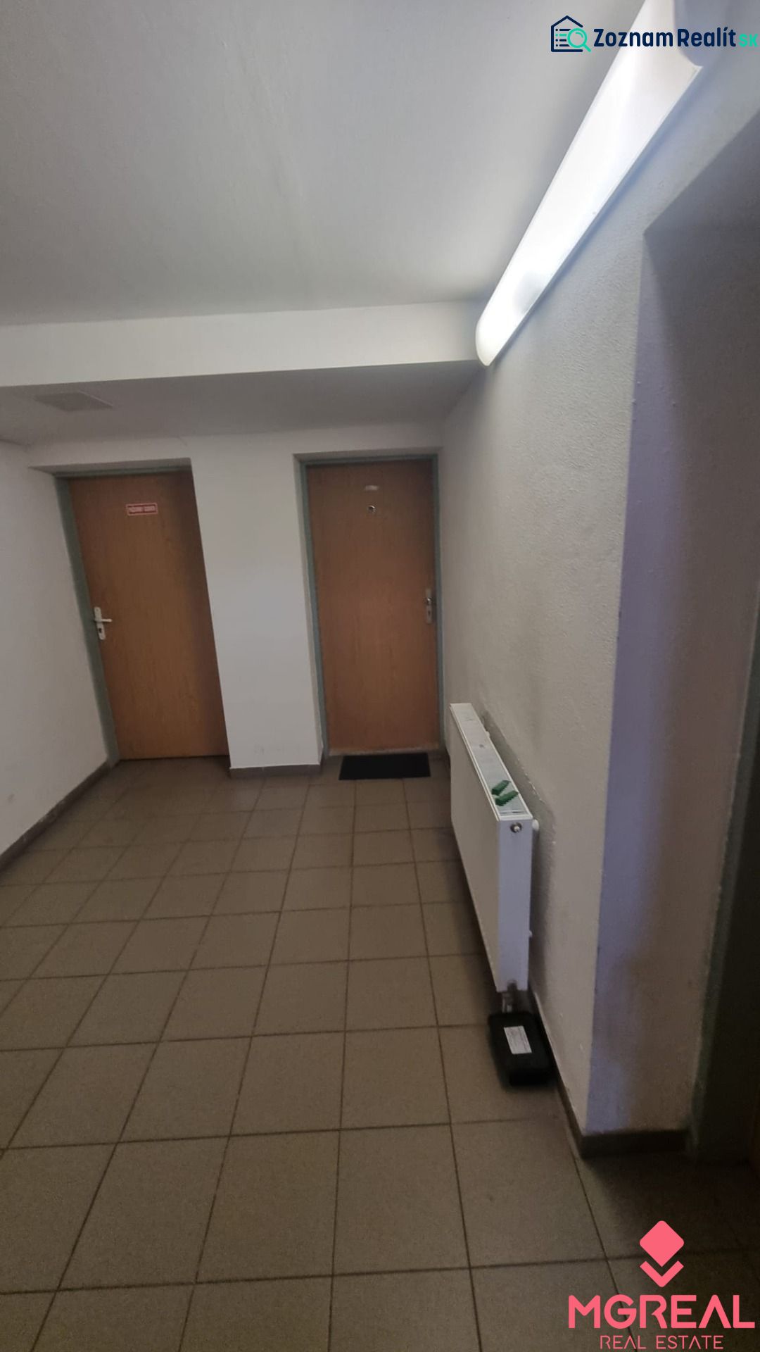 Entrance hall in a 2-room apartment with doors and a radiator, tiles on the floor.