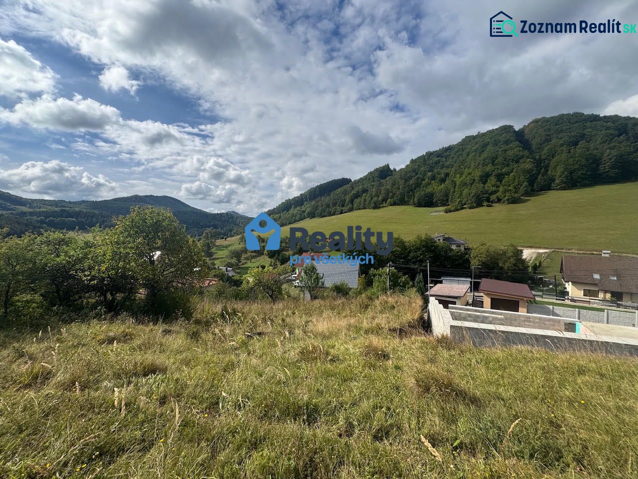 Residential plots in Považská Bystrica with hills and houses in the background.