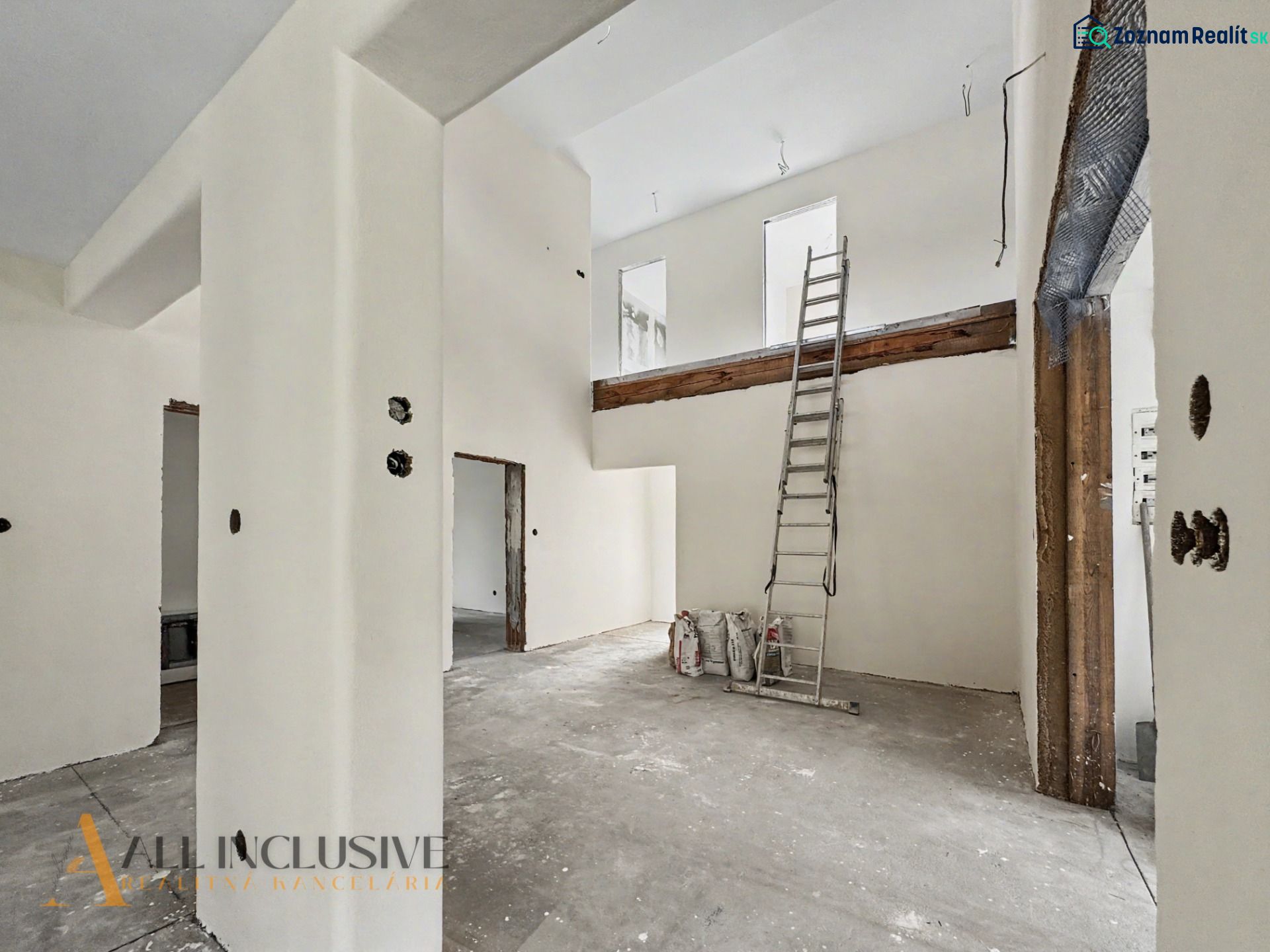 The interior of a family house under construction with a ladder and white walls.