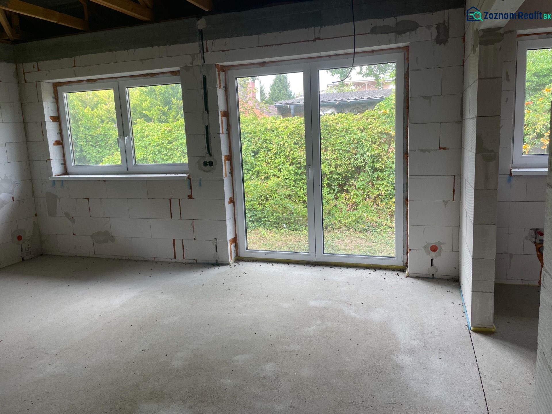 A room in a family house with large windows, view of the green outside.