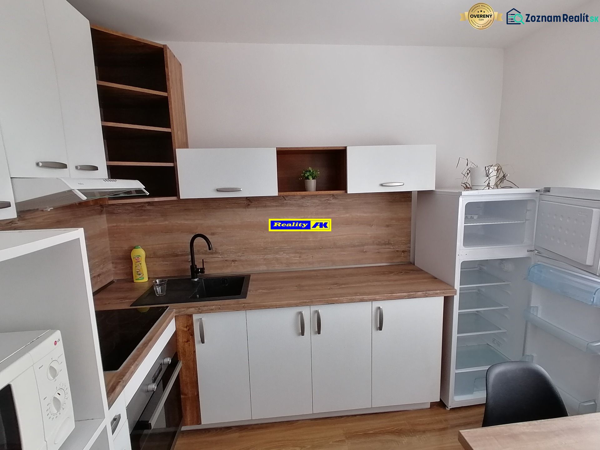 A kitchen in a studio apartment with a wooden decor floor and an open refrigerator.