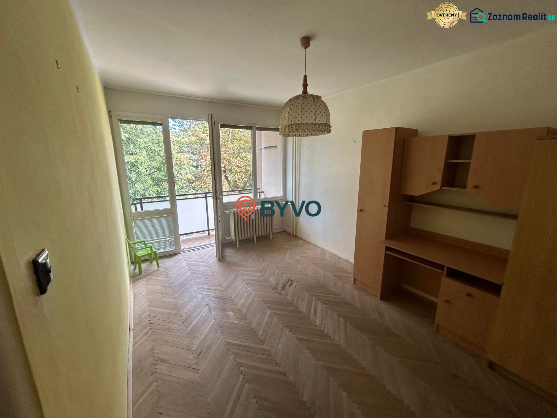A room with furniture, a wooden decor floor, a balcony in a 3-room apartment.
