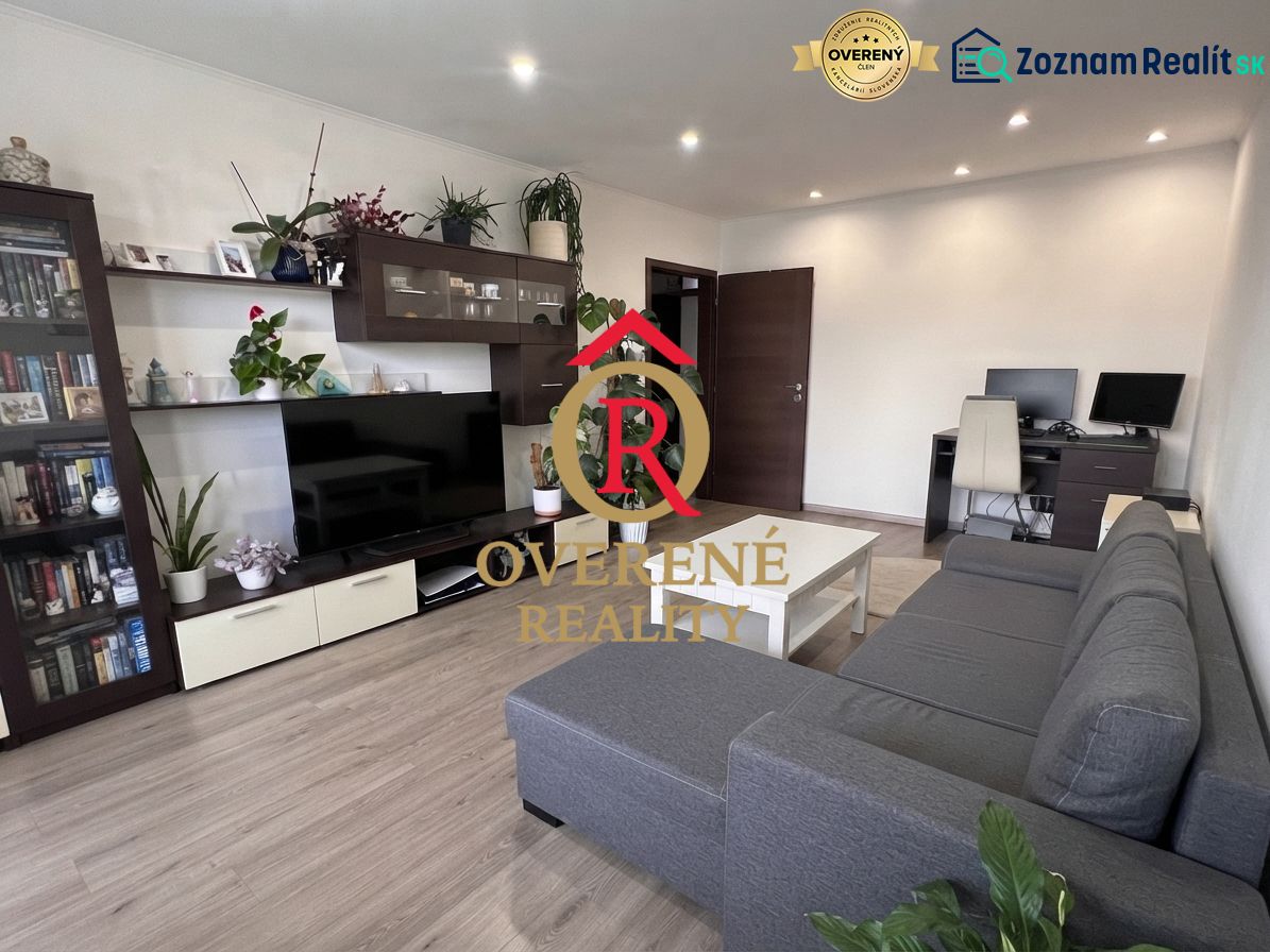 Living room with a sofa, wooden decor flooring, table, and shelves in a three-room apartment.