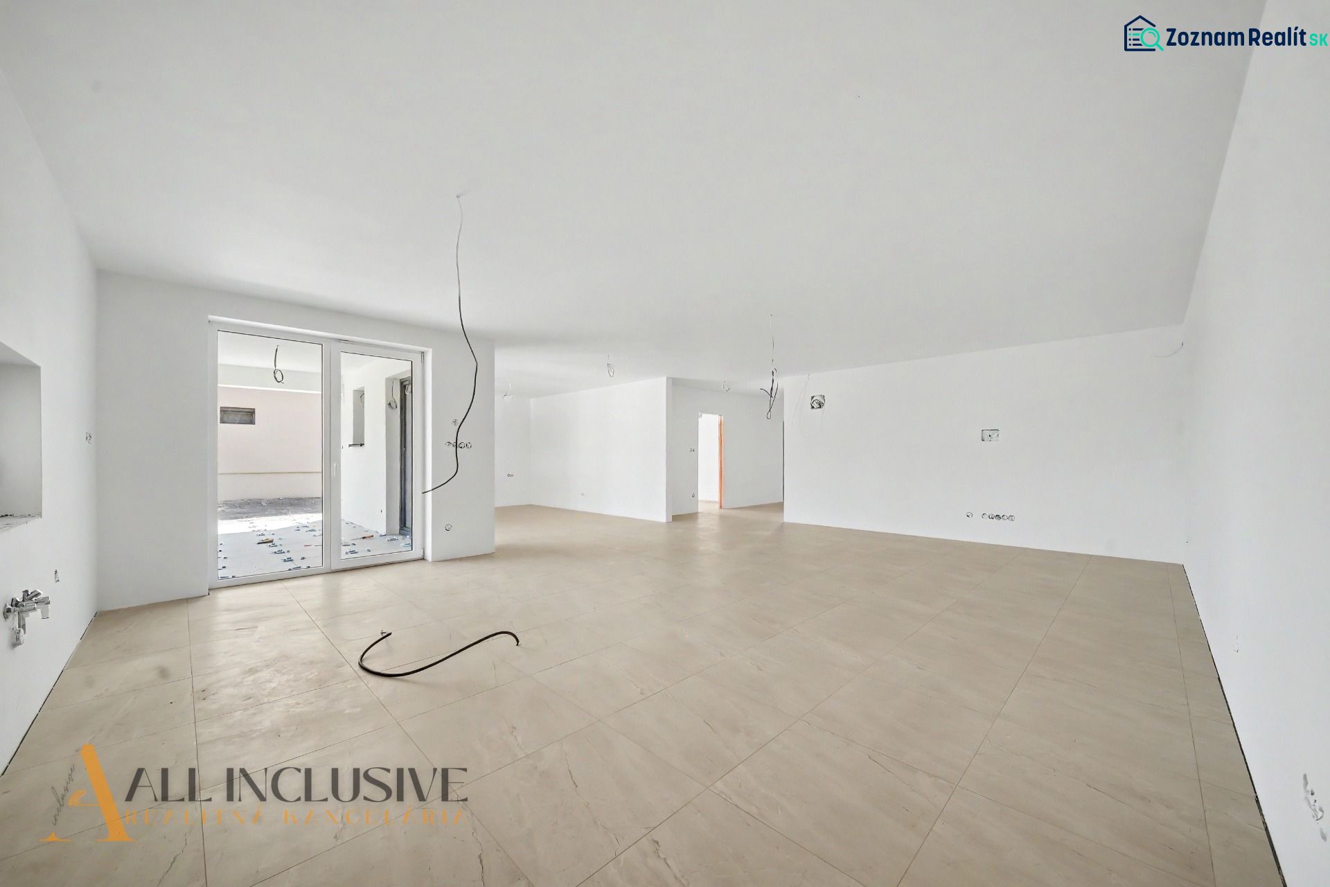 A spacious room with a wood-patterned floor, large window, and white walls.