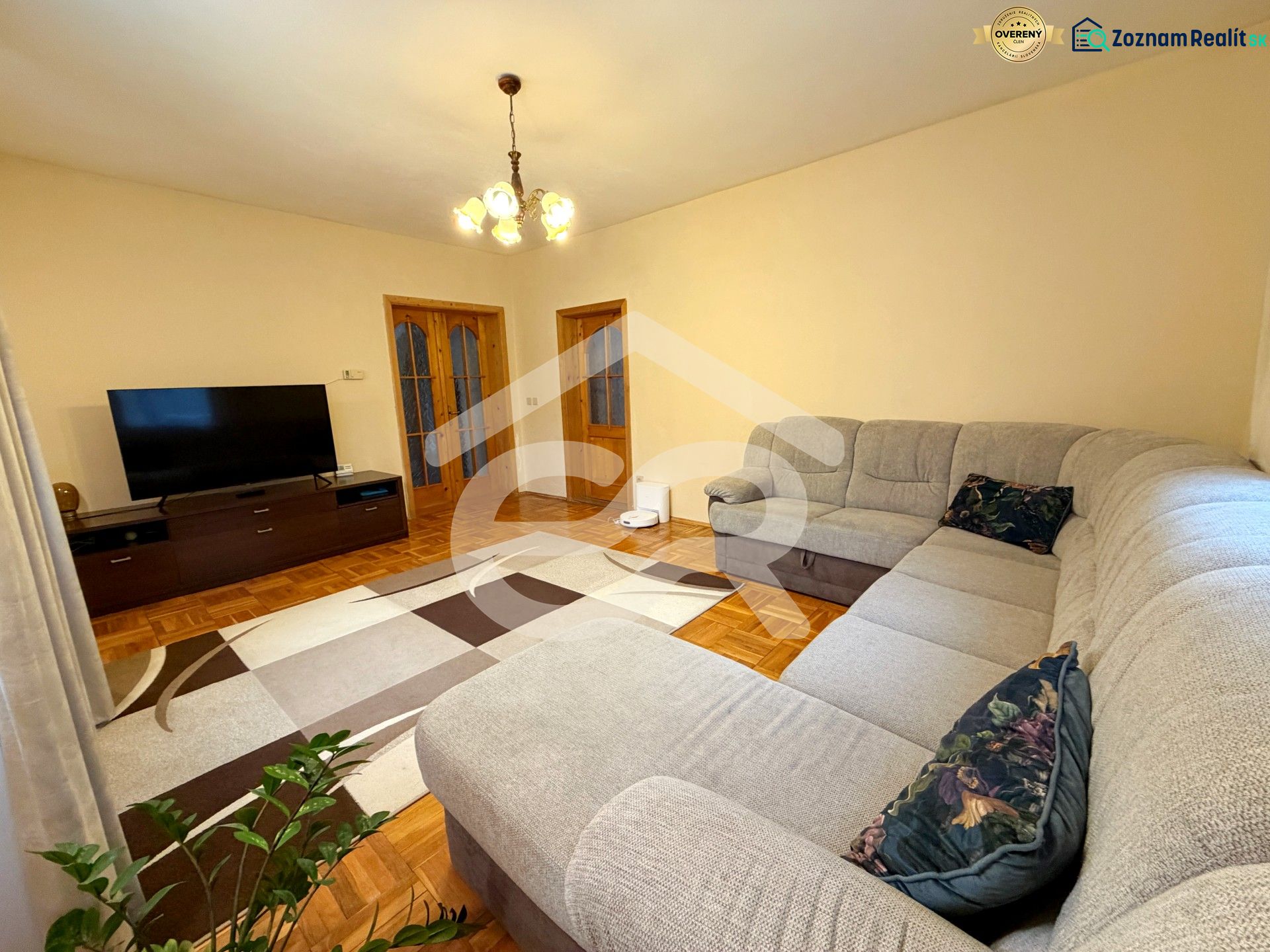 Living room with wood-patterned flooring, a large sofa, and a television in a family house.