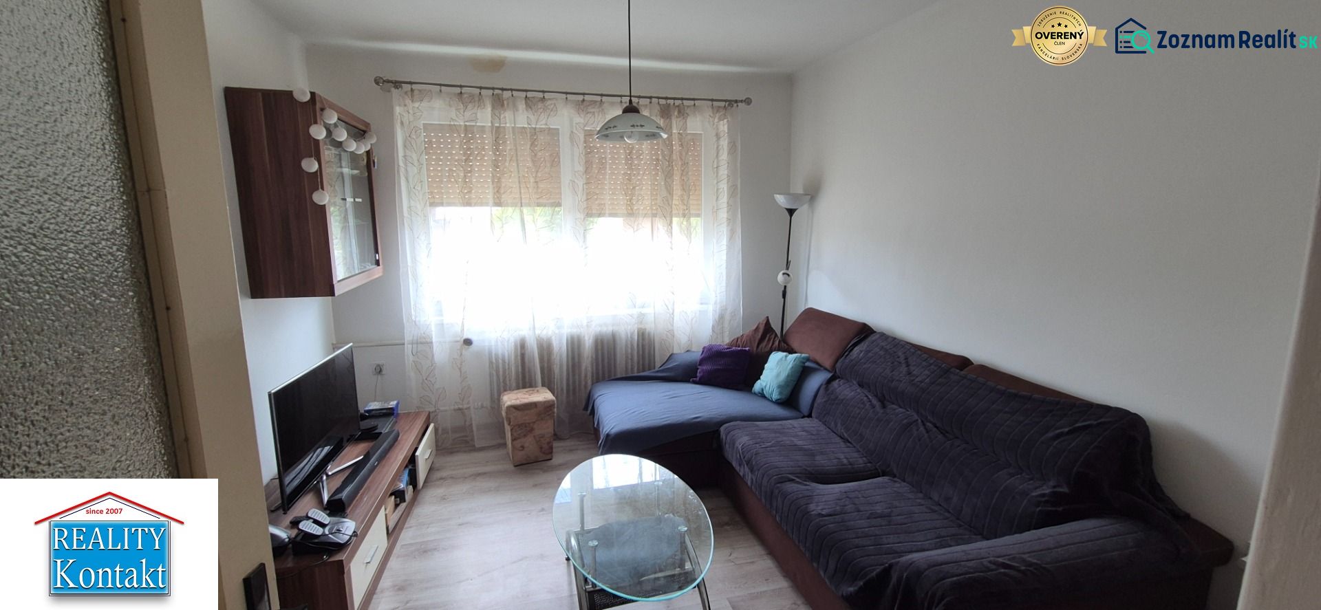 Living room in a family house with a couch, TV stand, and curtains.