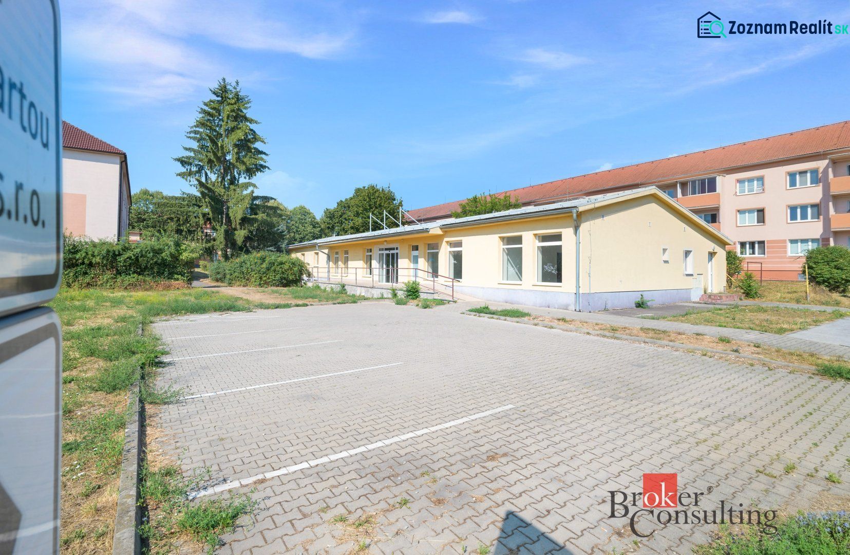 Commercial premises on Š. Moysesa in Žiar nad Hronom, parking lot and yellow building.