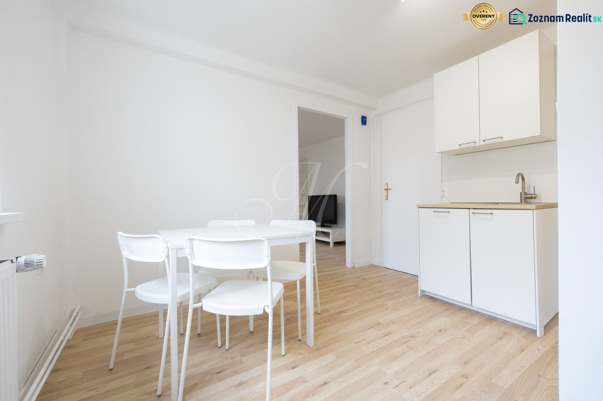 Dining area with a white table and chairs in a 2-room apartment, floor with wood decor.