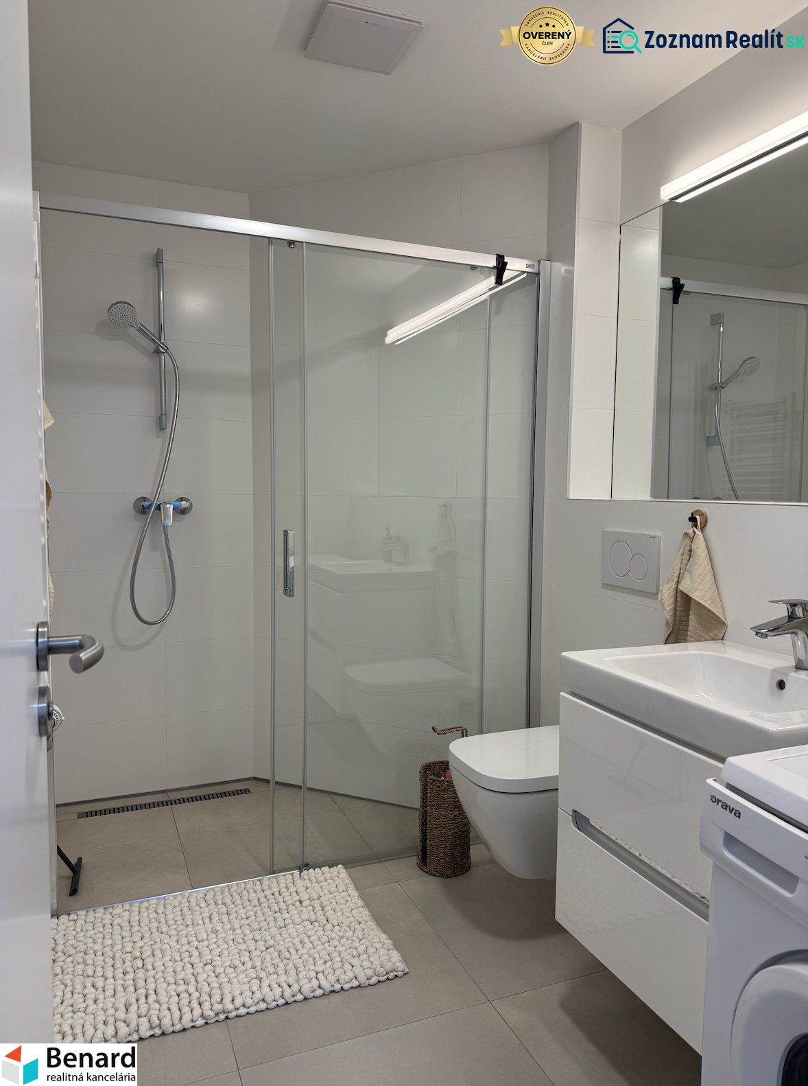 Bathroom with a shower, sink, and washing machine in a studio apartment.