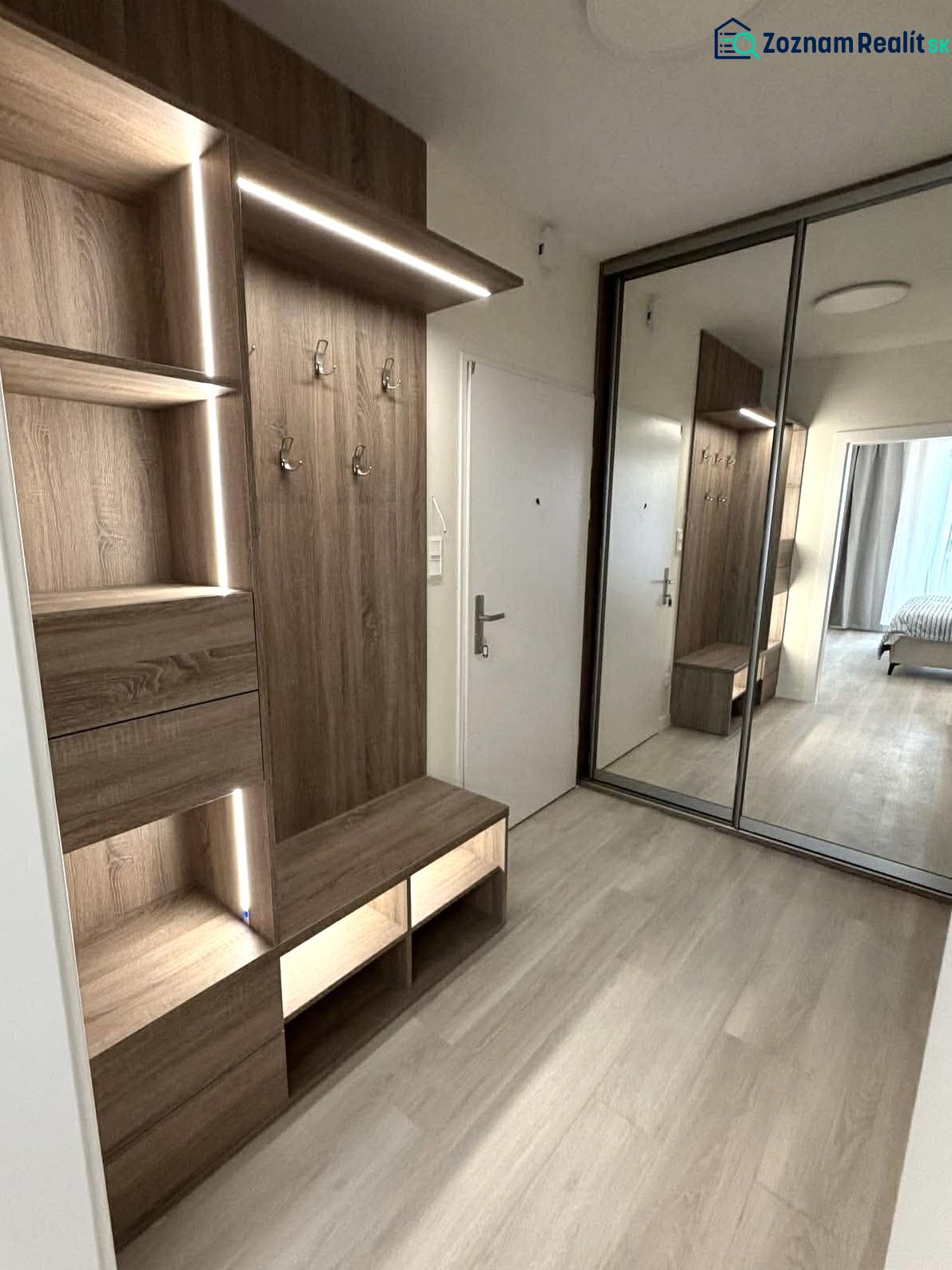 Entrance hallway in a 2-room apartment with a wooden decor floor and a built-in wardrobe.