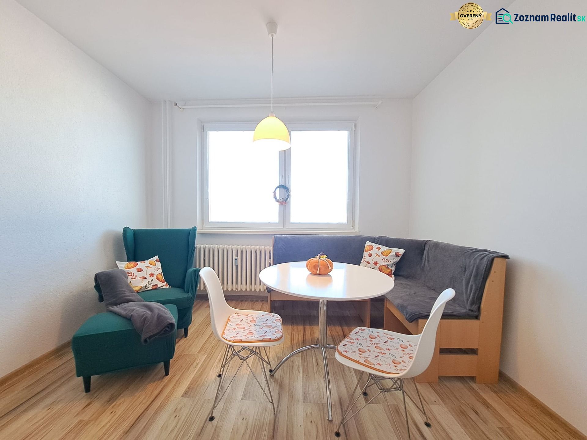 Dining room with an armchair, corner bench, table, and floor with wood decor in a 3-room apartment.