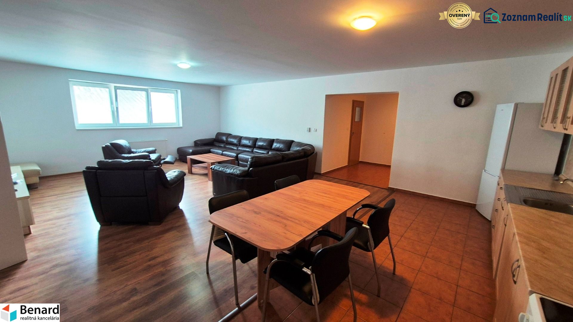 Living room with sofas, a table, a kitchen unit, and a wooden decor floor in a 3-room apartment.
