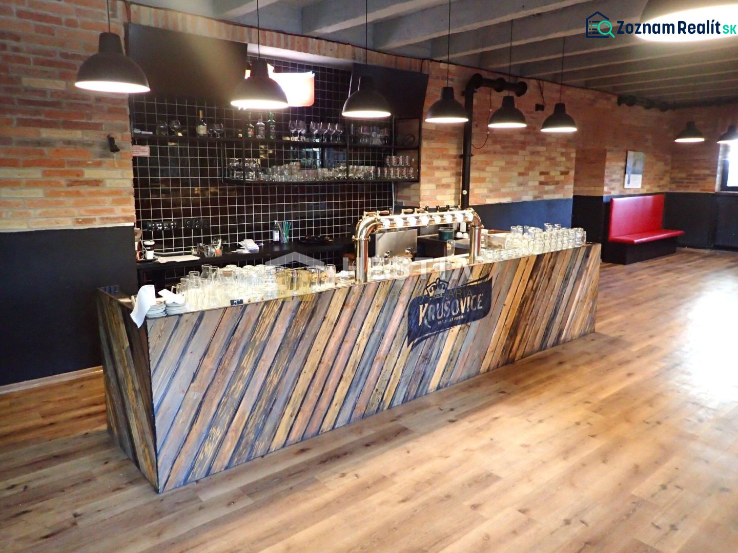 A bar counter in commercial premises with a wooden decor floor and a brick wall.