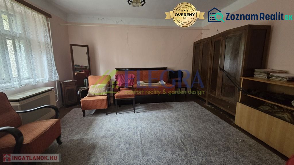 A living room in a family house with carpet flooring and wooden furniture.