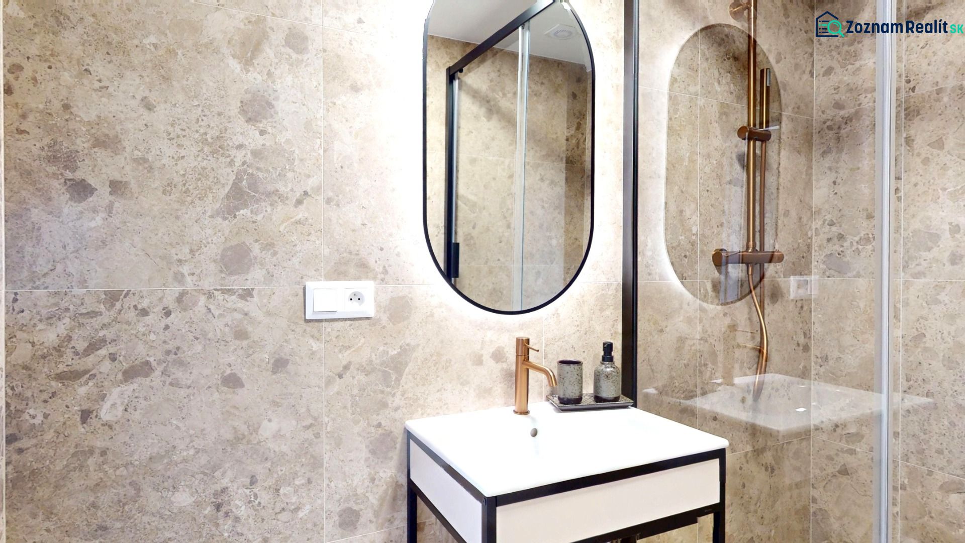 Bathroom of a 3-room apartment with stone tiles, a mirror, and a sink in a black frame.