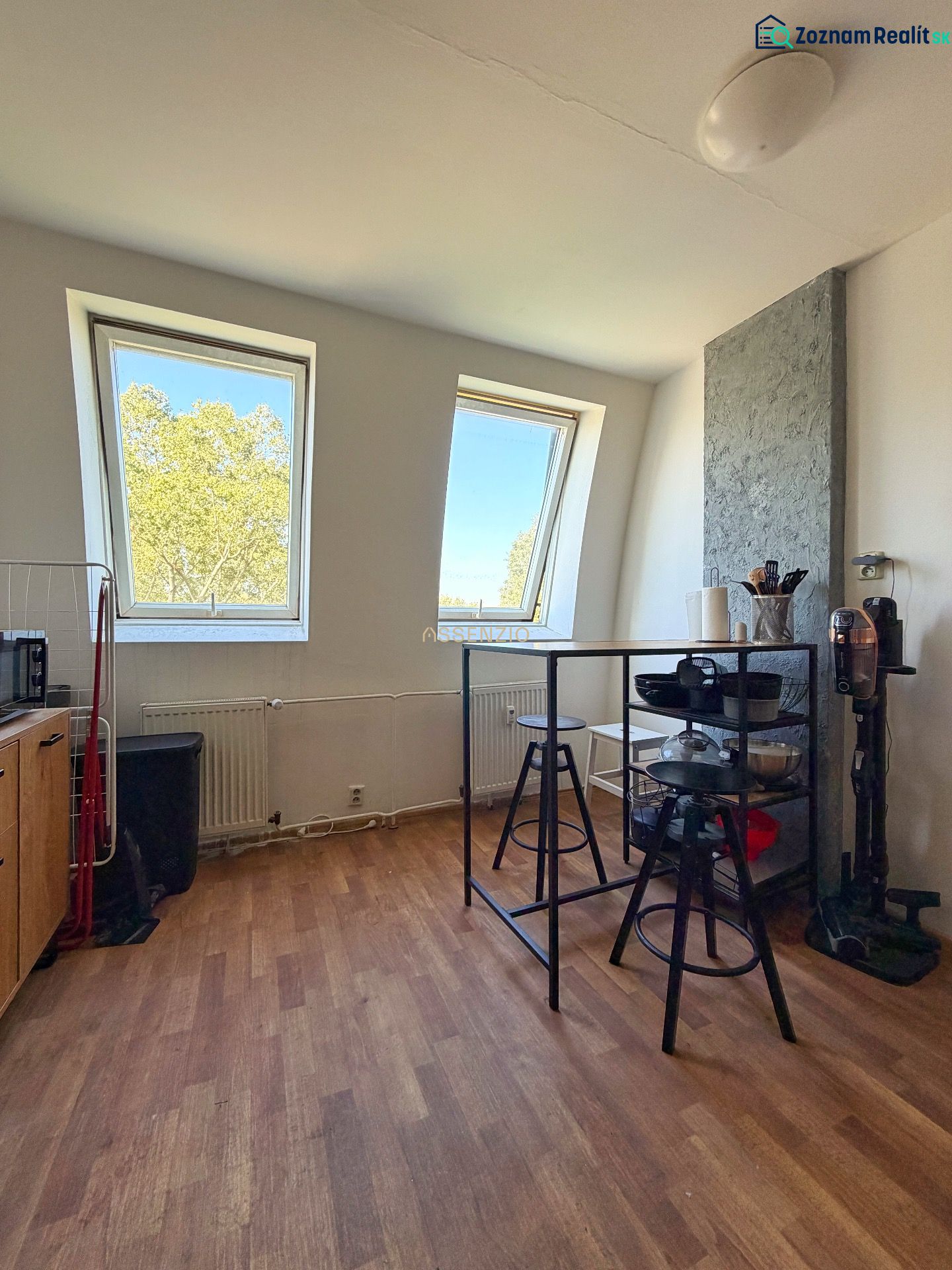 A kitchen in a 2-room apartment with a wooden decor floor and skylights.