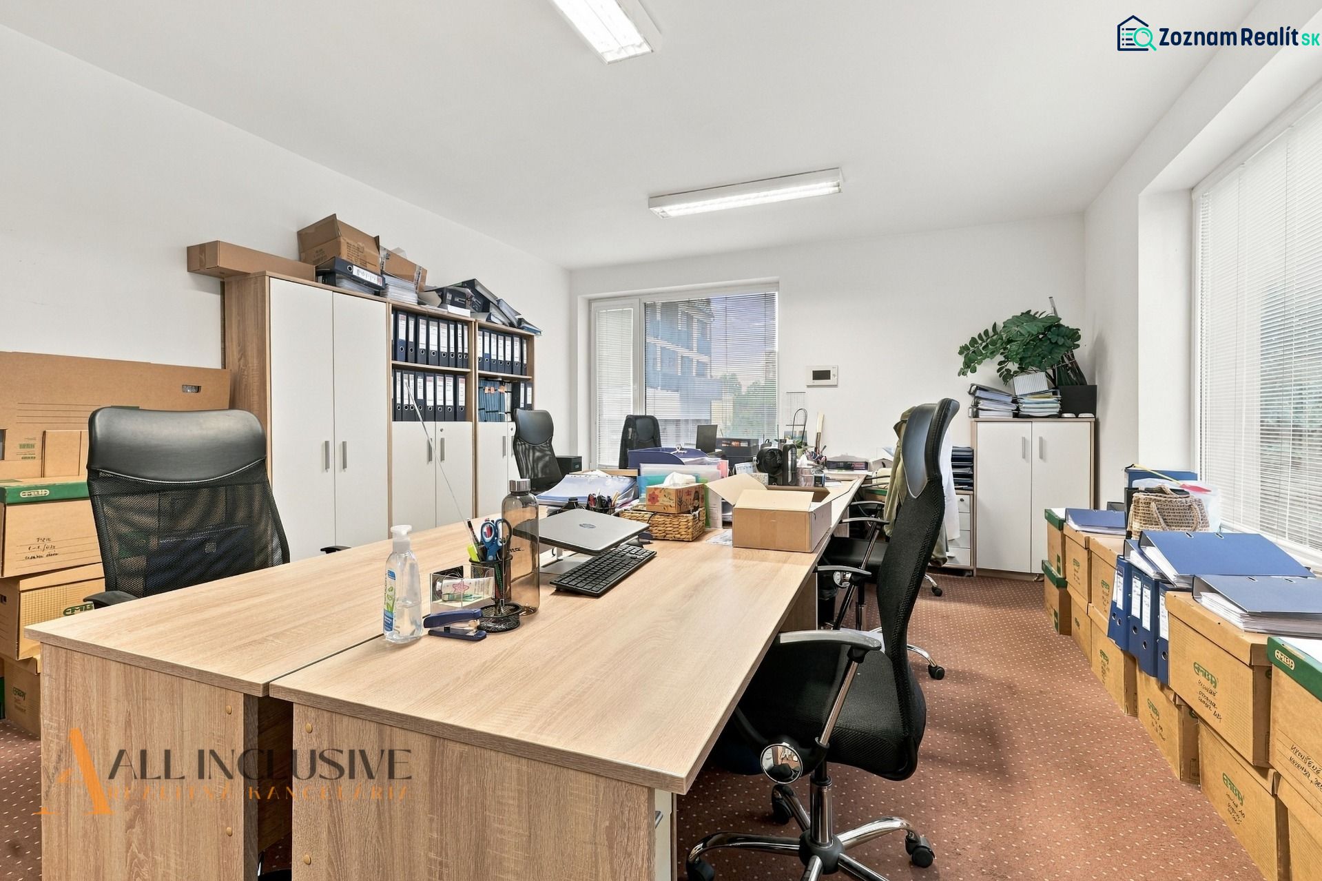 Offices with wood-patterned flooring, desks, chairs, and boxes full of documents.