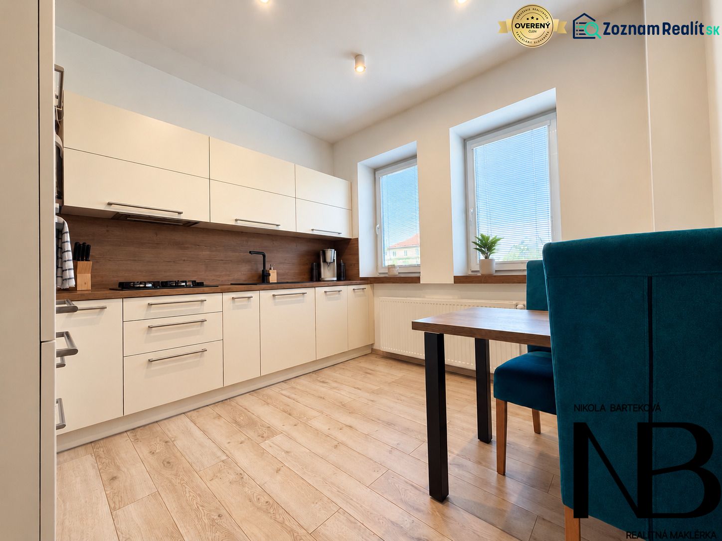 A kitchen with white furniture and a wooden decor floor in a 3-room apartment.